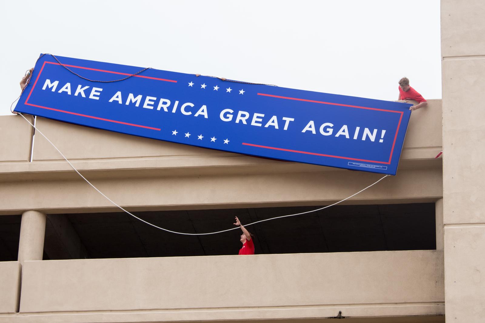 Workers attempt to hang a banne... campaign rally in Tulsa, Okla.