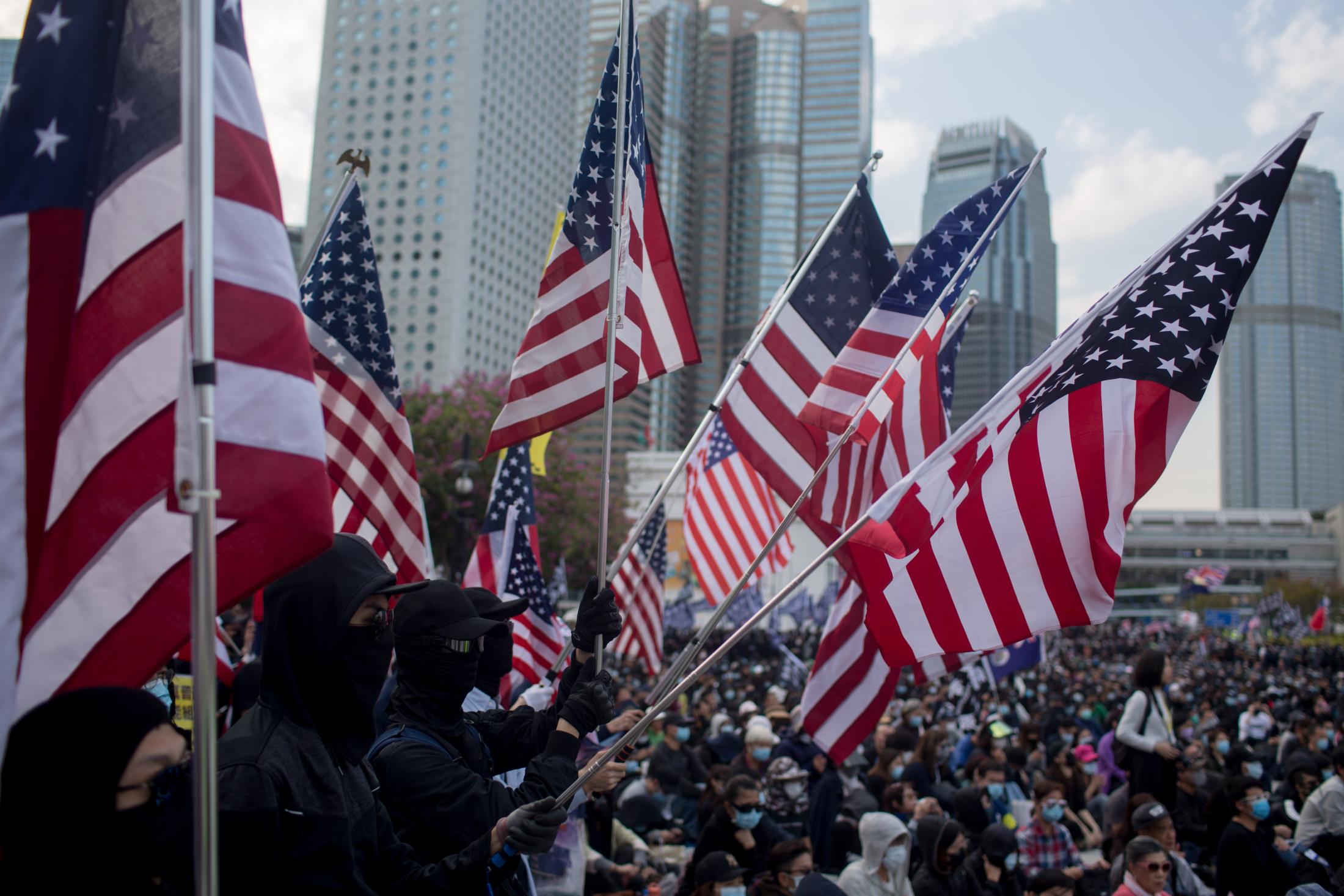 The Enemy of My Enemy - A group of pro-democracy demonstrators wave American...