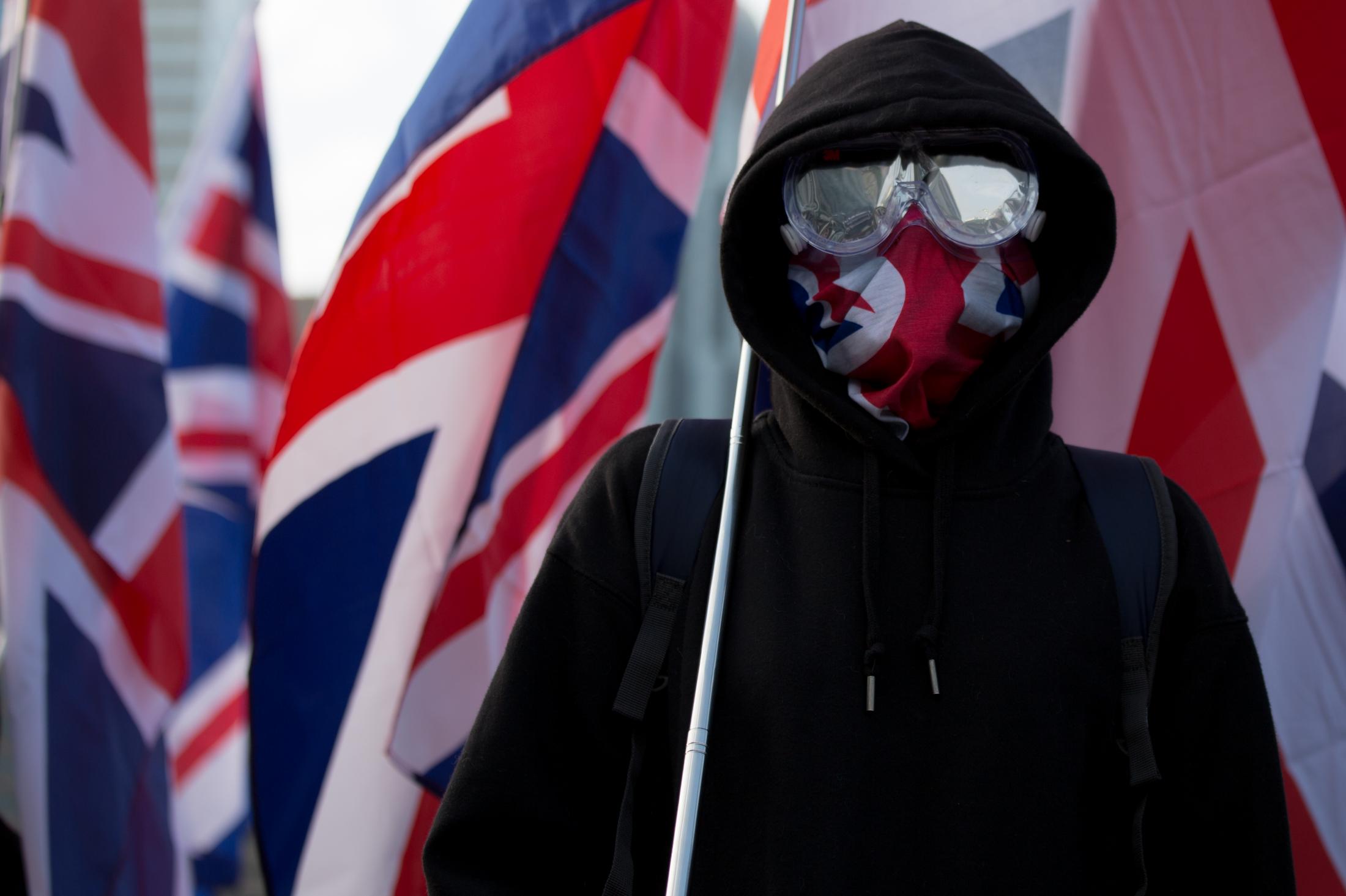 The Enemy of My Enemy - A pro-democracy protester stands surrounded by English...