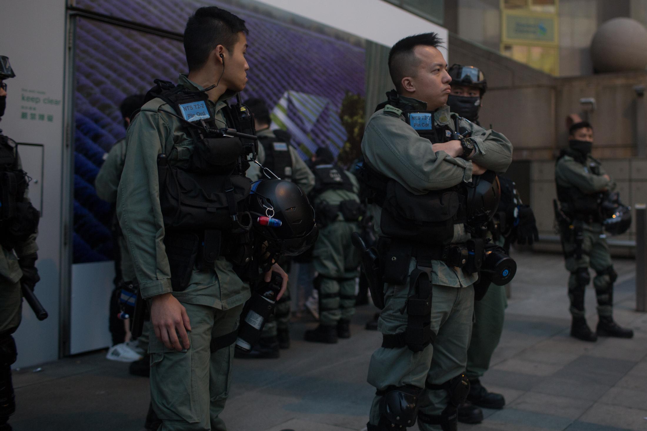 The Enemy of My Enemy - Riot police stand on a sidewalk to keep protesters and...