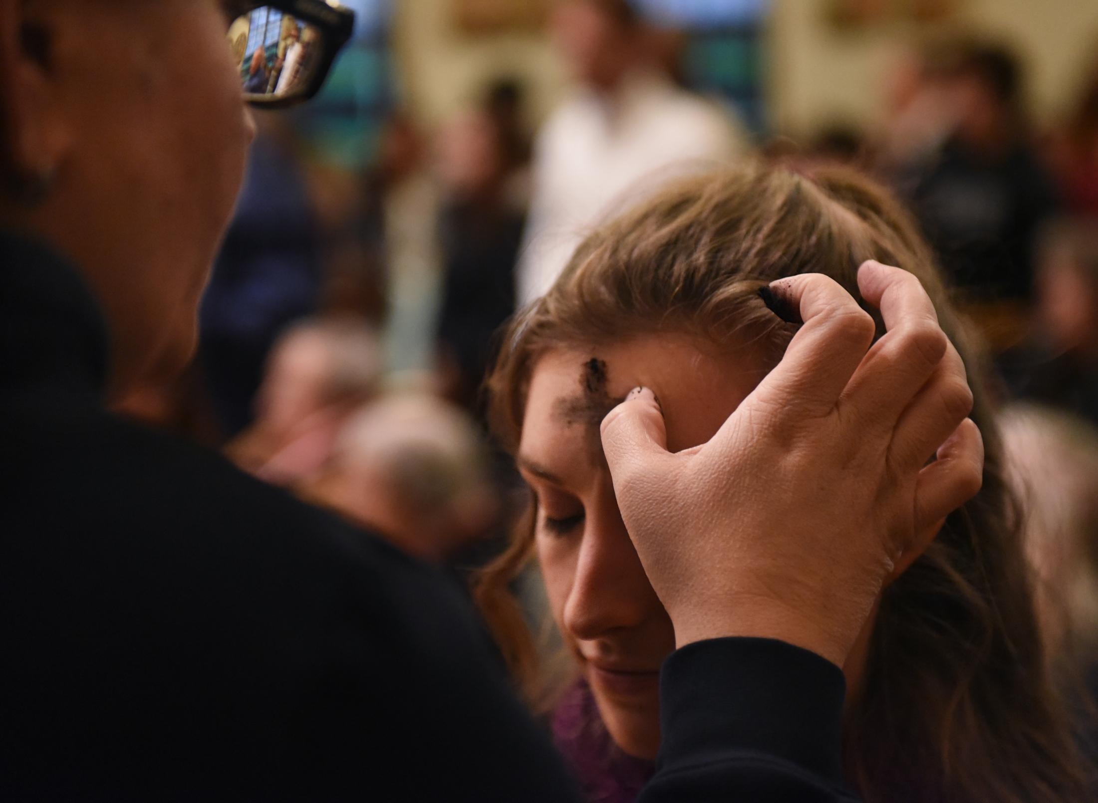 Emily Million receives a cross of ash during evening mass at Sacred Heart Catholic Church in Columbia. Traditionally, members of the Catholic Church receive crosses made of ash on their forehead, symbolizing repentance.