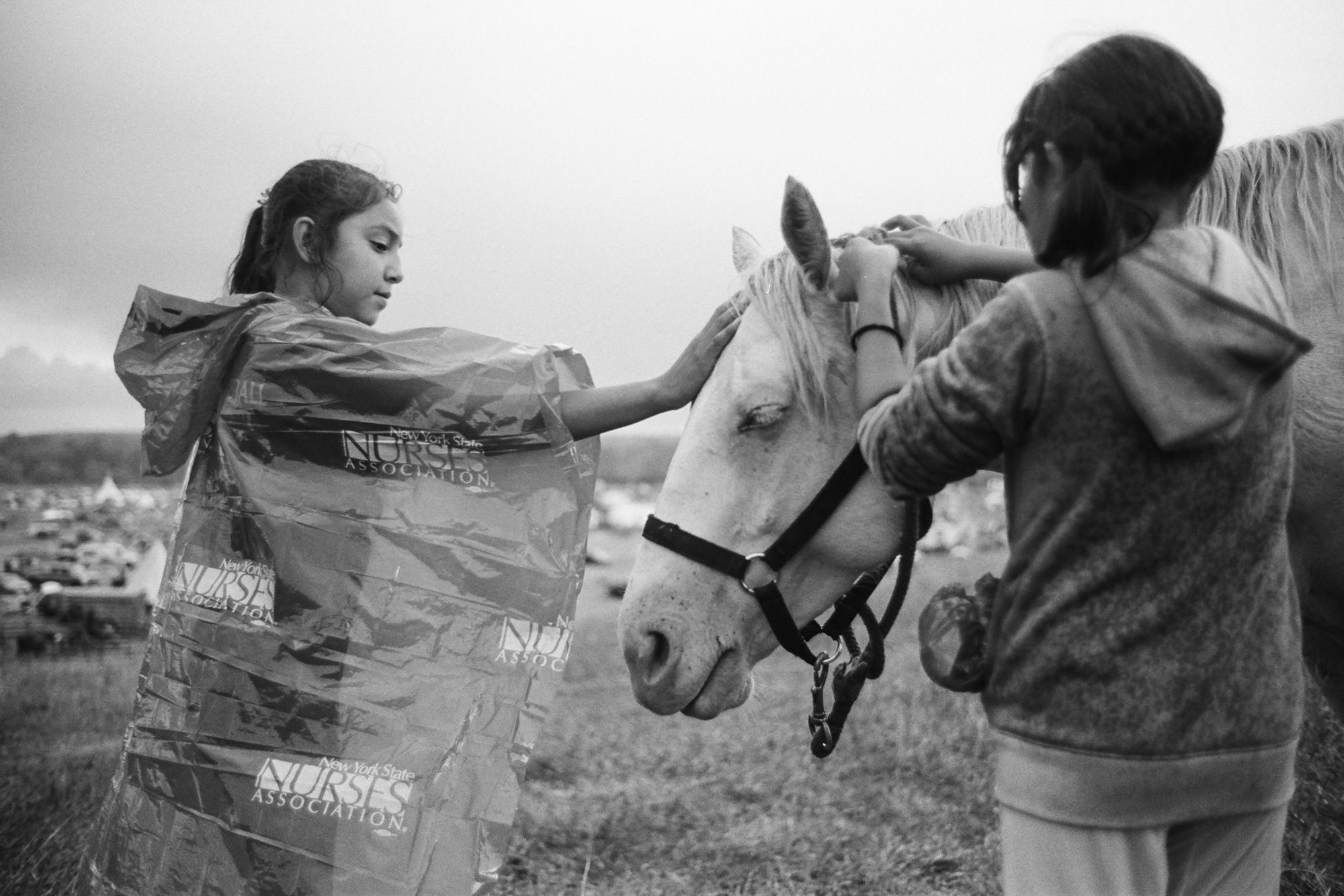 Standing Rock - Two girls tend to an albino horse in the rain. Shortly...
