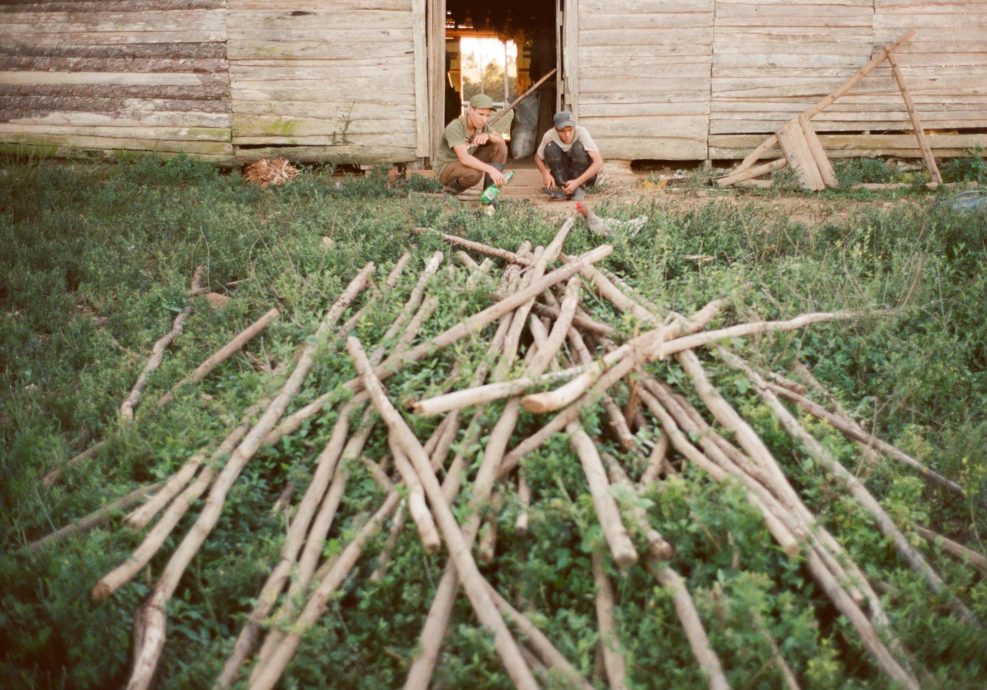 VI&Ntilde;ALES. Two teenage farmers, Richer and Osmani, fix a sticky set of pliers with oil on the Casa del Veguero farm. The wooden beams in the foreground are used to hang future sewn lines of tobacco leaves to dry on within the secadero.