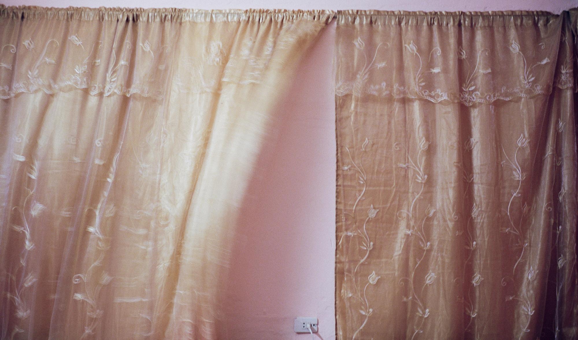 Tobaccoland - VIÑALES.  Curtains biilow from a fan in a humid...