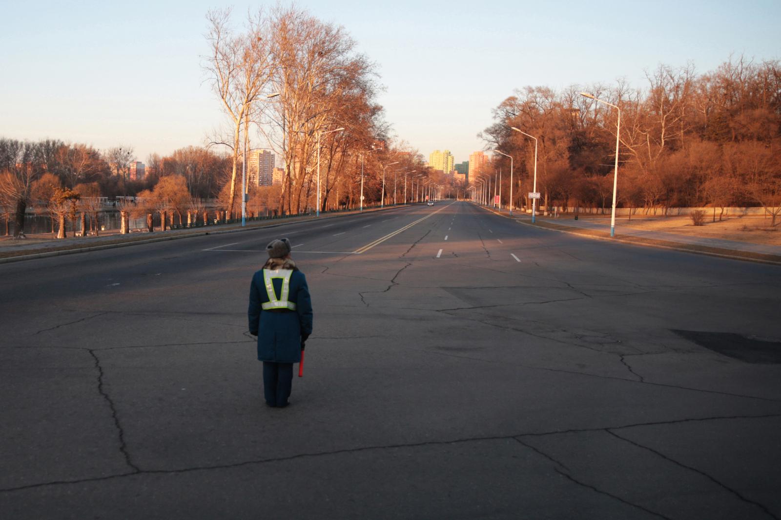 A traffic guard standing in the... empty crossroad at Pyongyang. 