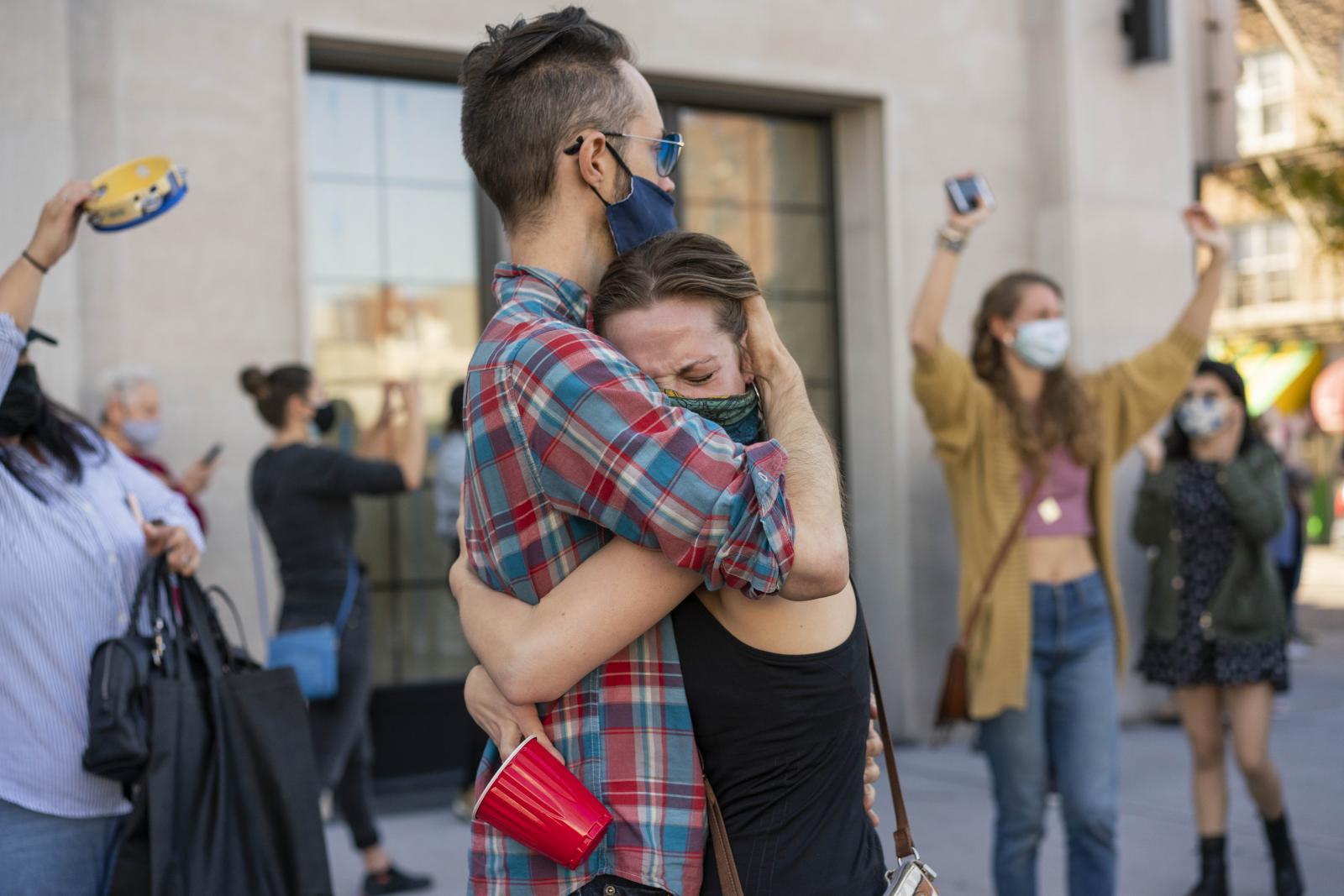 Two people embrace after hearin... Election against Donald Trump.