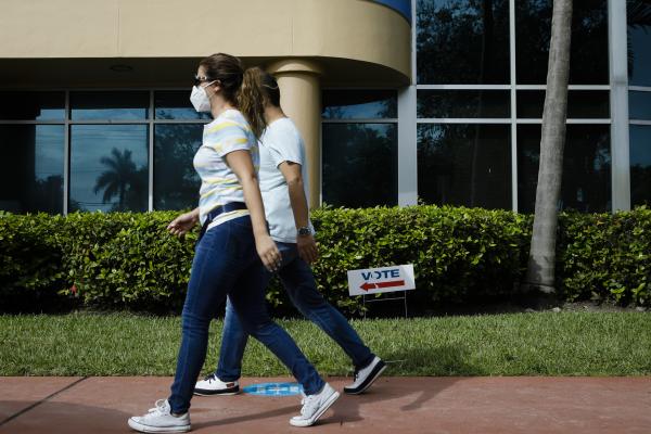 Image from 2020 - Presidential Elections @ Miami, FL - Voters walks past a "Vote" sign in an early...