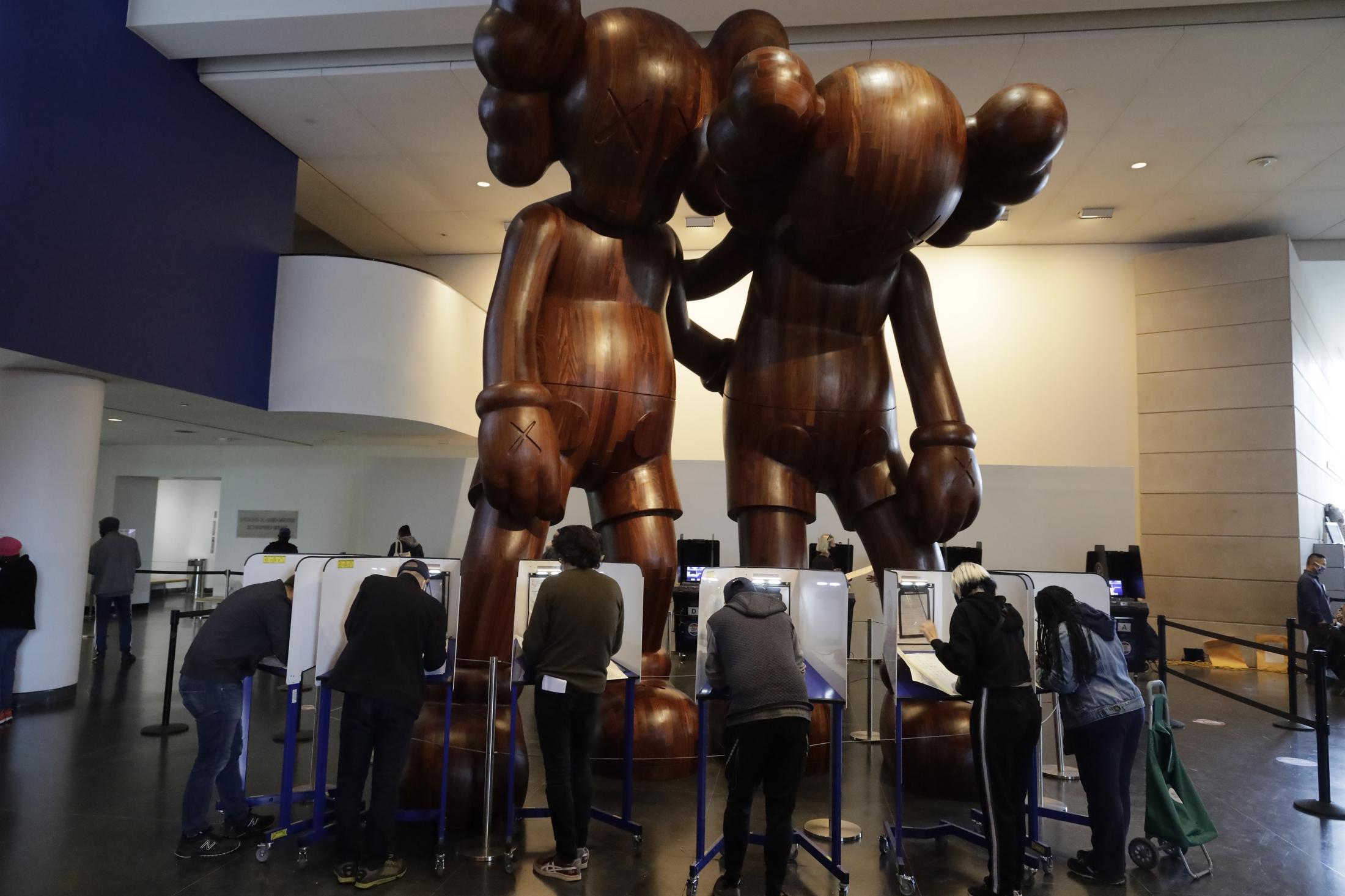 2020 Elections - Large wooden statues look upon voters as they cast their...