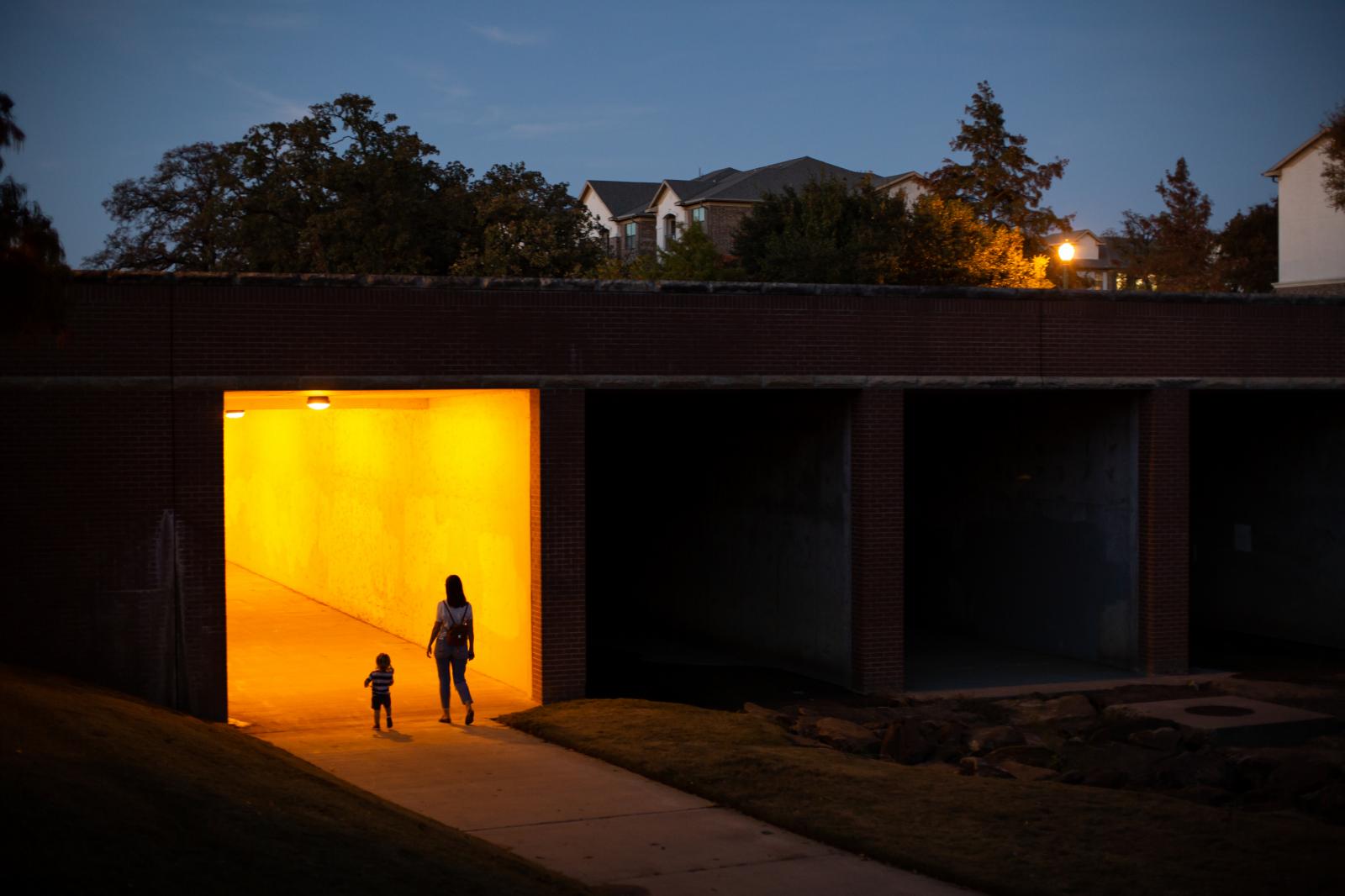 Thumbnail of 10/9/20 - A mother and son walk _at glows out of a city overpass.