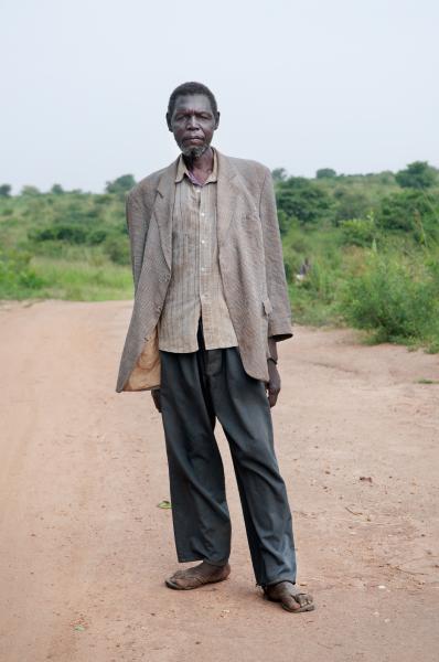 Image from Parenting the Missing - William Oryem stands on the road by his field close to...