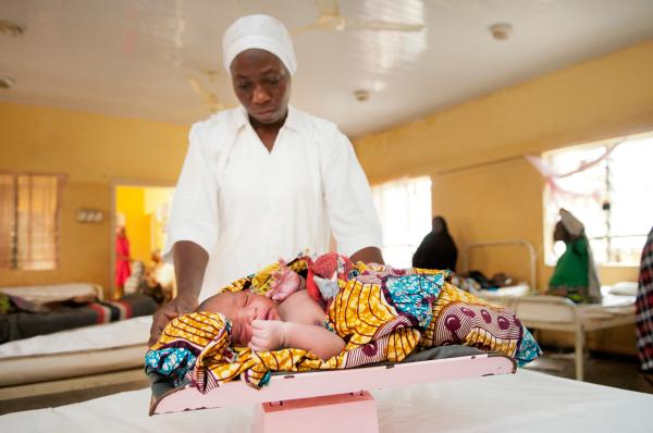 Image from NGO Work - Nurse Ladi Adamu weighs newborn Mohammed at Sumaila...