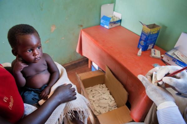 NGO Work - Young girl watches as nursing assistant Robert Tamale...