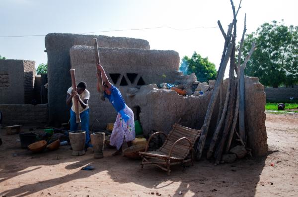 Image from NGO Work - Siblings pound millet in a yard of theri household close...