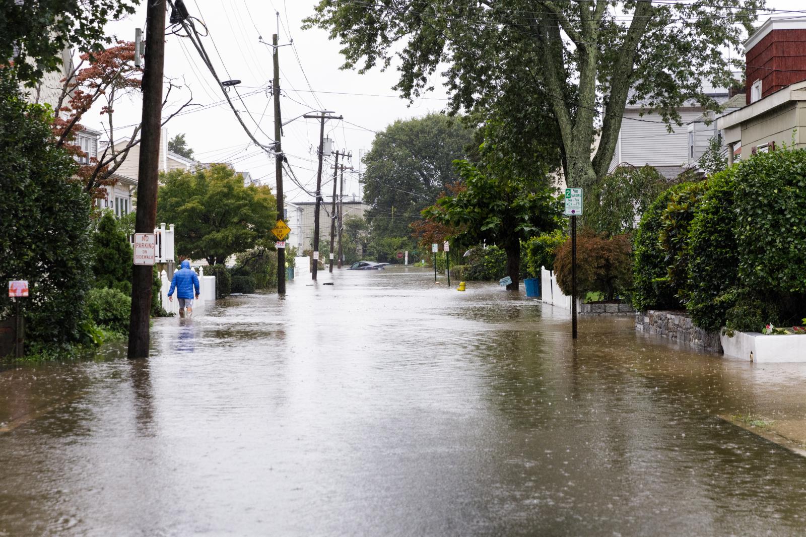 Man walks down Center Ave in do...vy rains on September 29, 2023.