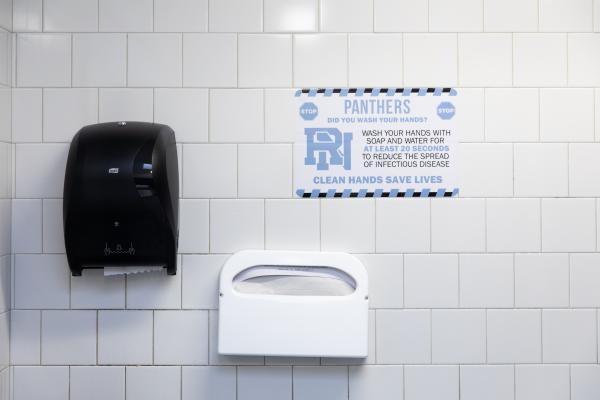 Spaces and Signs (COVID-19) - Wall posters in bathrooms remind students to wash their...