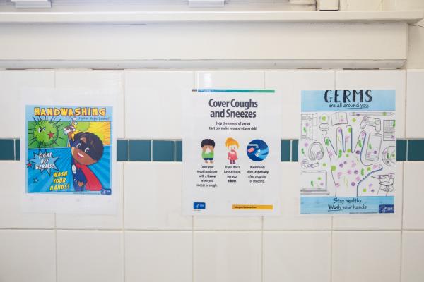 Spaces and Signs (COVID-19) - In the bathrooms, posters remind students how to stop the...