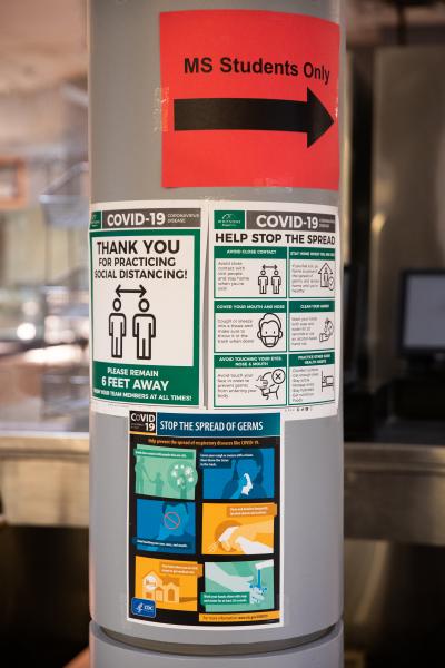 Spaces and Signs (COVID-19) - Posters in cafeteria remind students how to prevent the...