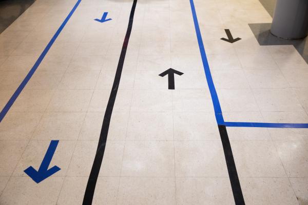 Spaces and Signs (COVID-19) - In the cafeteria, arrows on the floor remind students...