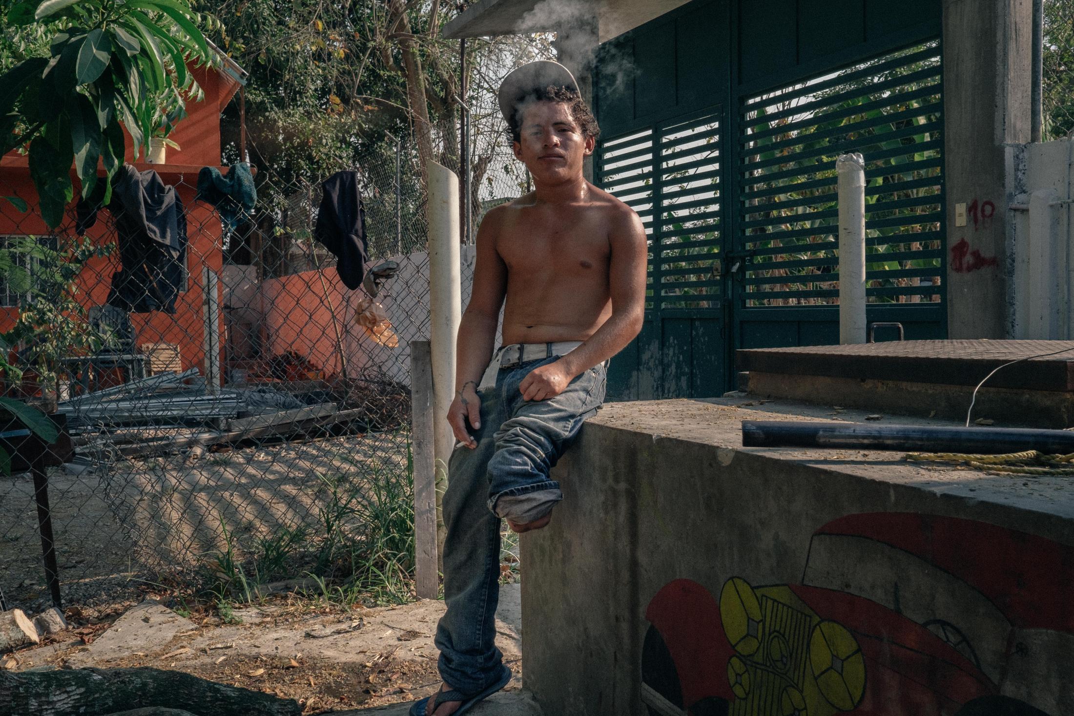 Southern Border - Carlos, 21, takes a break while chopping wood for the...