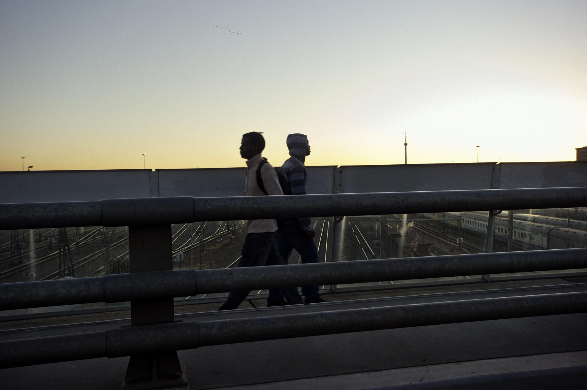 Into the shadows - Johannesburg, South Africa.
June 2011.
Men walking the...