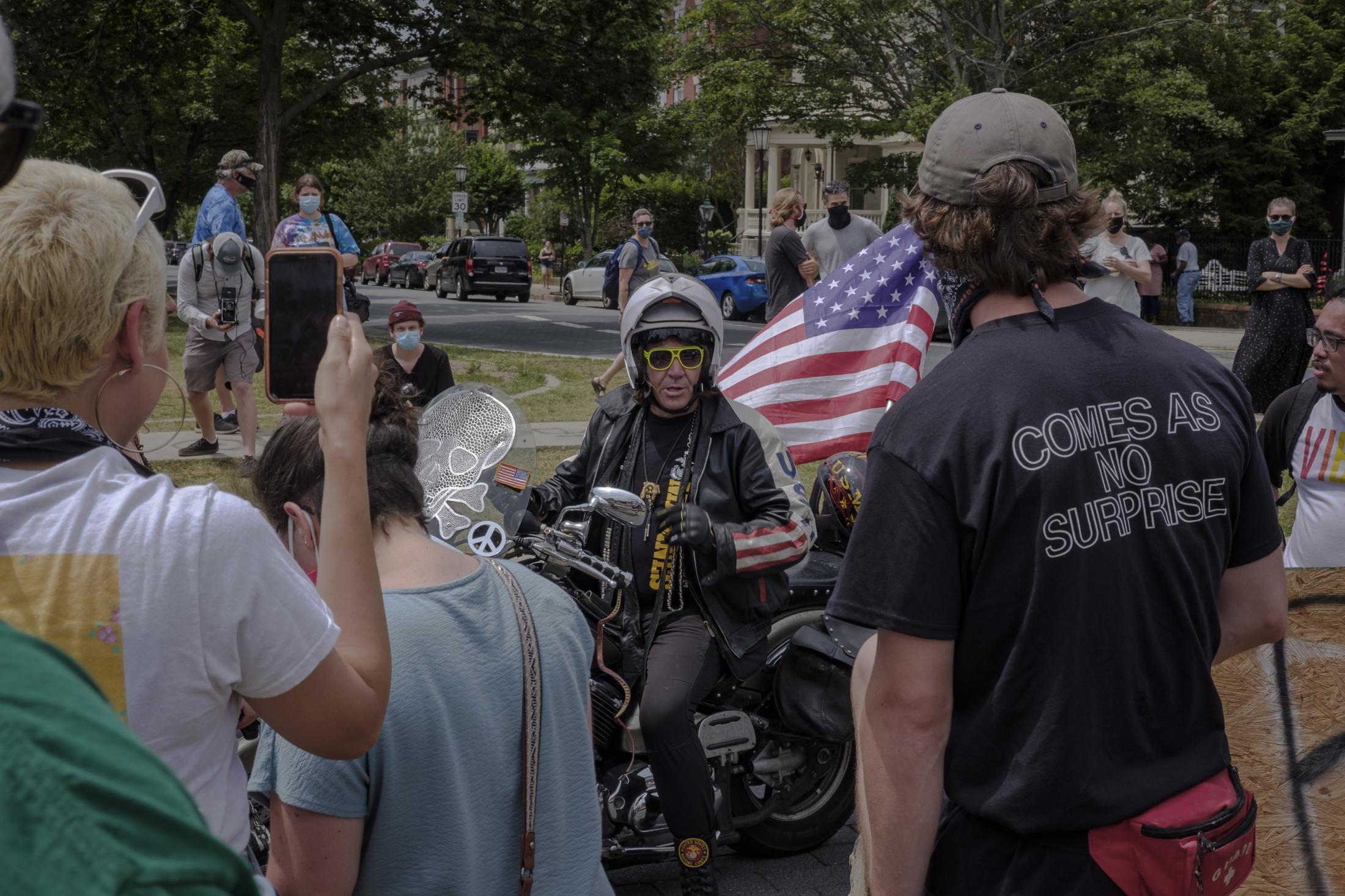 RICHMOND, VA - June 20, 2020: A man on a motorcycle carrying the United States flag arrives where people gather at the Robert E. Lee memorial and begins an altercation with supporters of the event. To celebrate the "Juneteenth," Richmond residents gather to honor those who have been killed by police officers and to protest police brutality on June 21, 2020 at Monument Avenue. The monument has been claimed by the community and has become a healing space where parents take photos with their children, play basketball and share a meal on the now proclaimed "Marcus-David Petters Circle". The Robert E. Lee memorial has been renamed in honor of the young Marcus-David Petters, who was shot and killed by a Richmond police officer on May 14, 2018. Photo: Carlos Bernate for The New York Times.