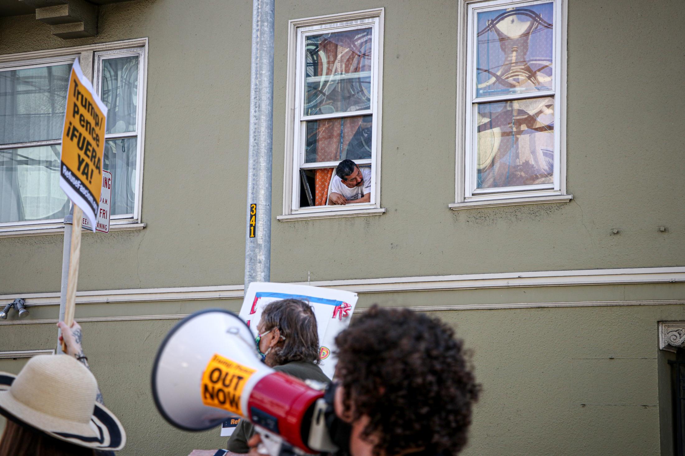 Democracy March SF - A resident leans out from his window to look at the...