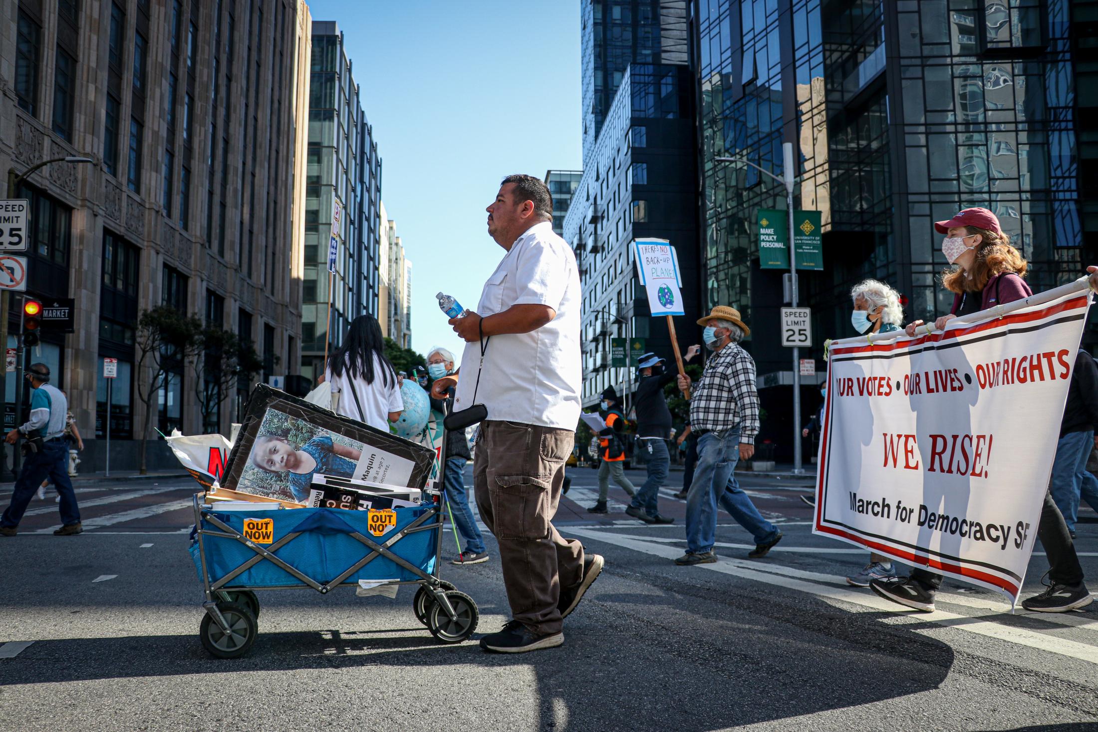 Democracy March SF - A man pushes the cart with photos of a few children who...