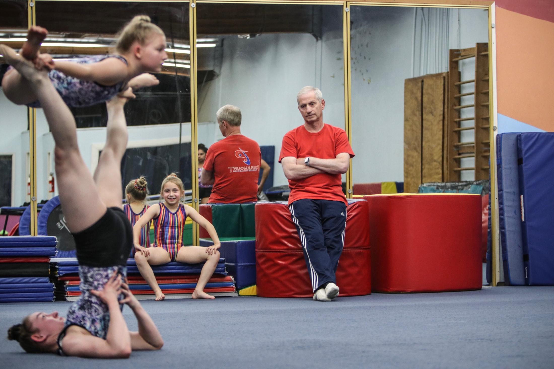 Gymnast Training - Coach Anatoliy Solodar watches Hope Takahashi balance her...