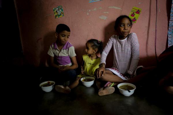 CARACAS, VENEZUELA - APRIL 12: Children of Barrio UniÃ³n Sector Las Casitas eat soup prepared and donated by Alto Restaurant in the house of a neighbor on April 12, 2019 in Caracas, Venezuela. Local NGOs offer food to those in need, especially elderly people and children. "Barriga Llena CorazÃ³n Contento" Foundation has been supporting a nursing home and two soup kitchens in the community of Mesuca, Petare for more than three years. There are five Restaurants that collaborate preparing food from Monday to Friday. Each restaurant has its own recipe but all are made based on instructions from a nutritionist. Political and economic crisis has triggered a food emergency in Venezuela. Most supermarkets and shops do not offer a wide variety and amount of food and goods due to the shortage that affects the country. To struggle with semi empty shelves, Venezuelans have to navigate street stalls and vendors to get eggs, corn and wheat flour and rice which are the basis of the Venezuelan diet. According to the 2018 survey on life conditions ENCOVI, conducted by three local universities, 89% of people consider their incomes are not enough to afford a proper diet. Six out of 10 said they had gone to bed hungry because they did not have the money to buy food. International Monetary Found estimates a 10 million percent inflation for Venezuela in 2019 with skyrocketing rises in the price of food and goods, increasing the number of Venezuelans unable to access to a healthy nutrition. According to FAO Early Action on Food Security report 2019, Venezuela is in alert due to food insecurity and has no consistent humanitarian response plan. (Photo by Eva Marie Uzcategui/Getty Images)