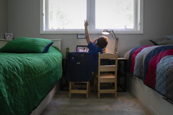 A student raises his hand while he is attending online distance learning from home in Miami, Florida, U.S., on Thursday, Sep. 03, 2020. Photographer: Eva Marie Uzcategui/Bloomberg