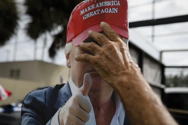 A hand holds a placard depicting U.S. President Donald Trump's face at John F. Kennedy Public Library in Hialeah, Florida on October 19, 2020. Eva Marie UZCATEGUI