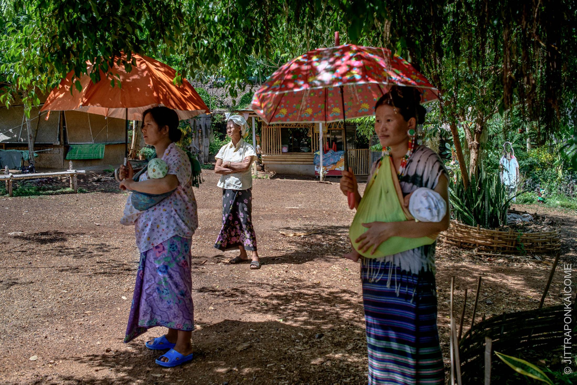 Kayaw, a tribal wearing big earrings and Kayan long neck women are waiting to received food handouts at a tourist hill tribe village in Mae Tang - Chiang Mai, Thailand.
