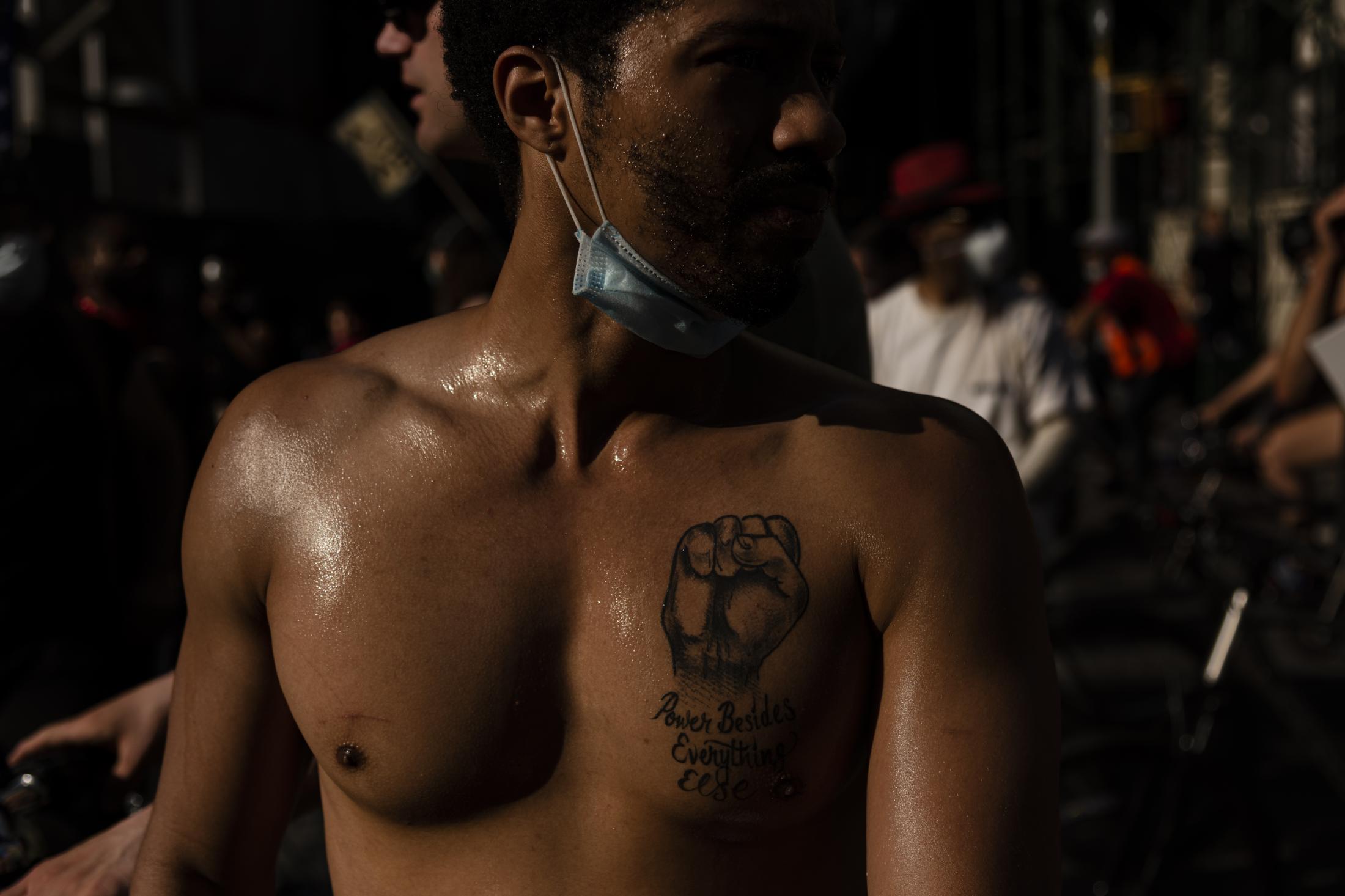 A man showing a tattoo of a rising fist that reads &quot;Power Besides Everything...
