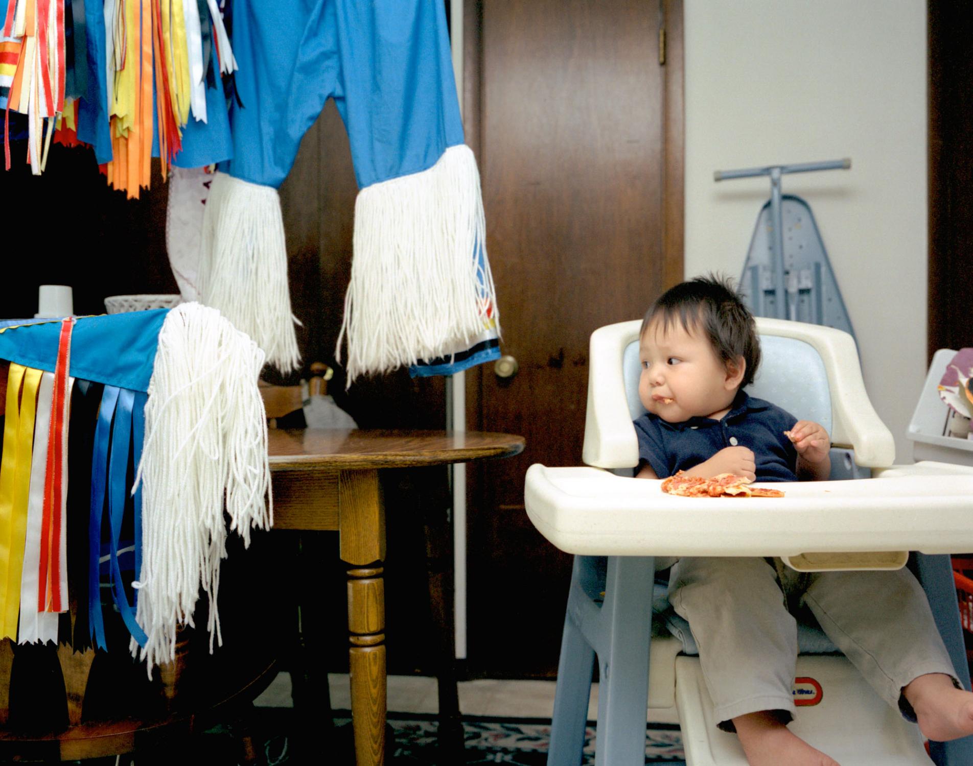 American Moments - Native American baby Teak (1) sits in his high chair in...