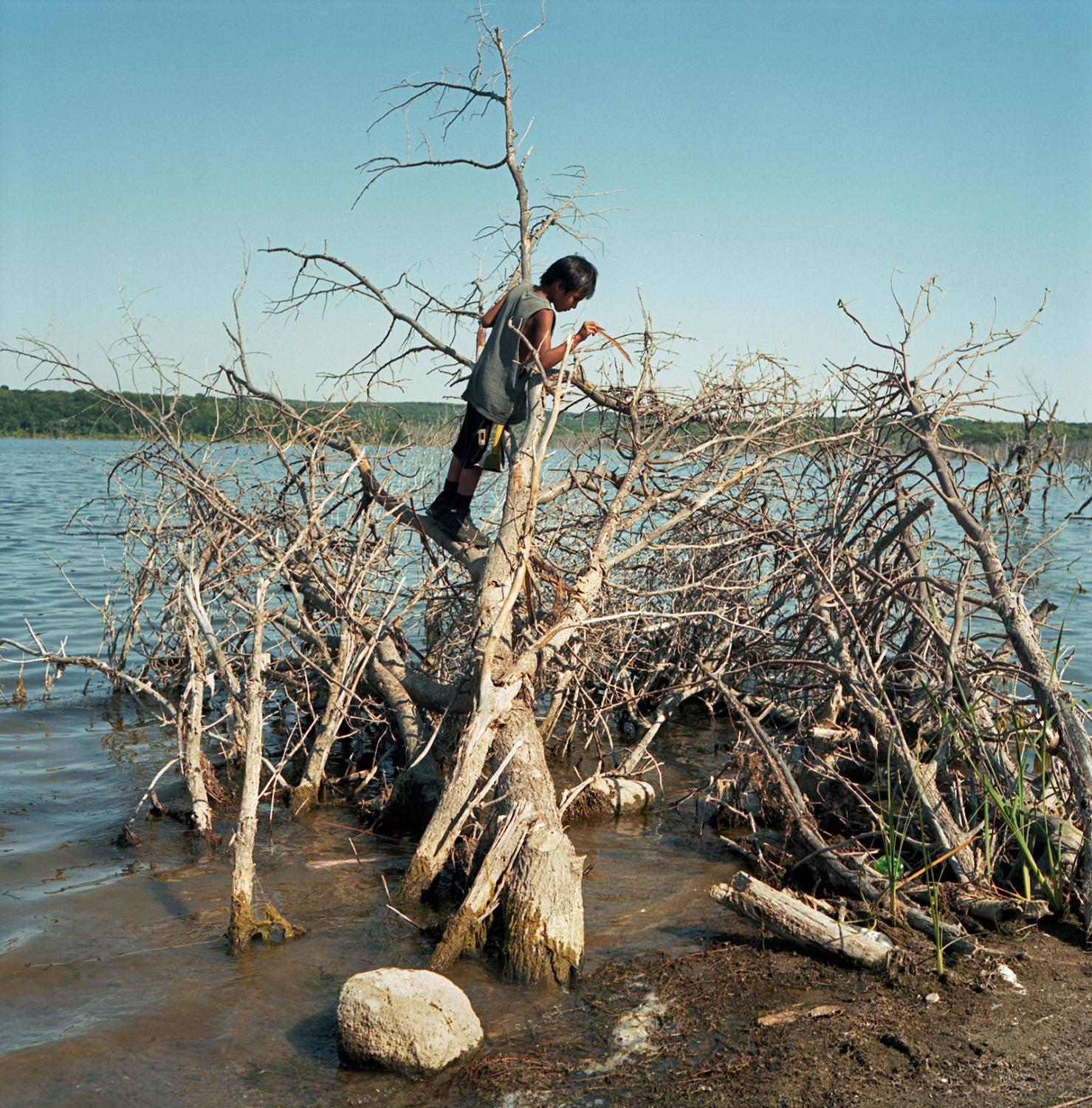 Young boy playing in the dried up bushes along the shore of Spirit Lake. Located in an isolated and economically languishing area of North Dakota,...