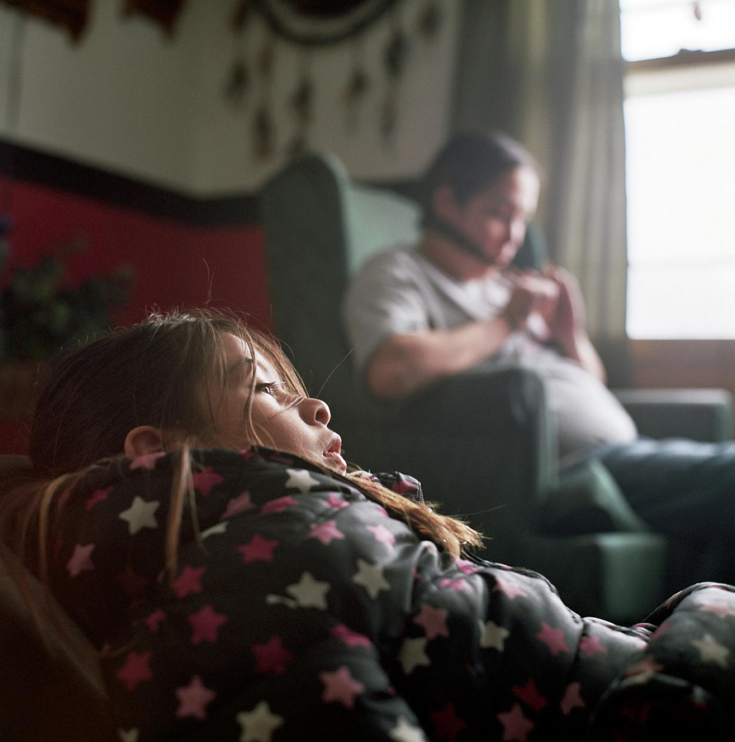 Spirit Lake - Taylor Anderson, age 8, watching TV with her mother Casey...