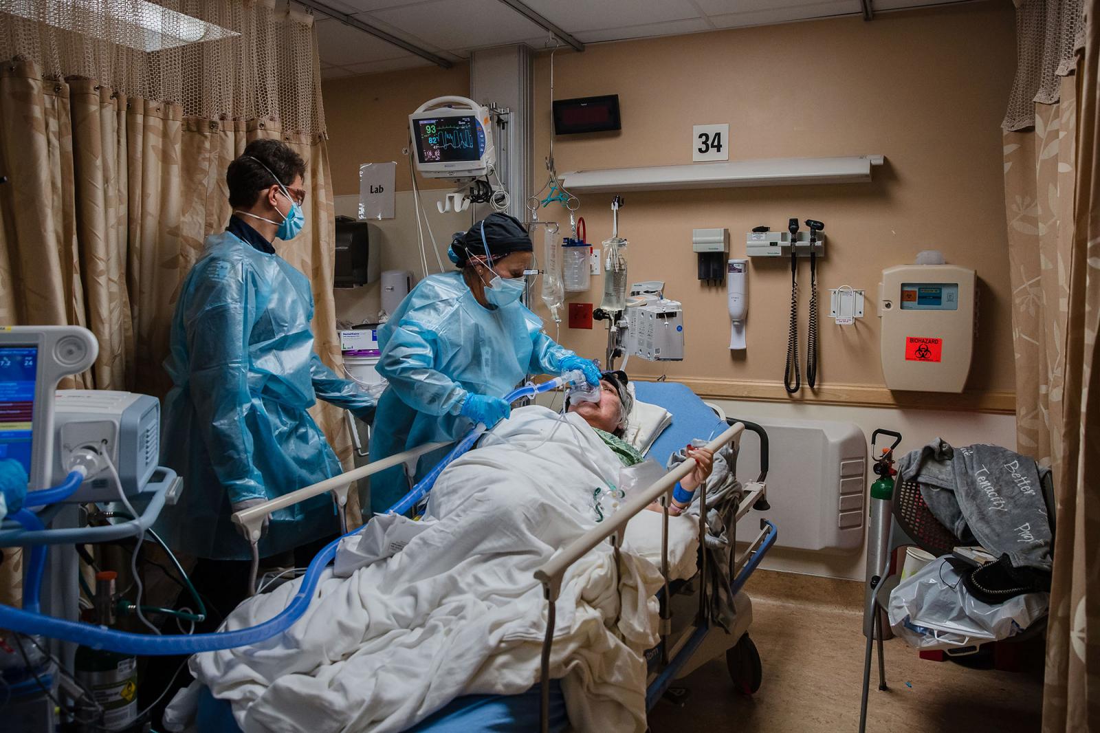 Health Care workers use a continuous positive airway pressure (CPAP) machine on a Covid-19 patient who is having difficulties breathing in a Covid holding pod at Providence St. Mary Medical Center in Apple Valley, California on January 11, 2021.