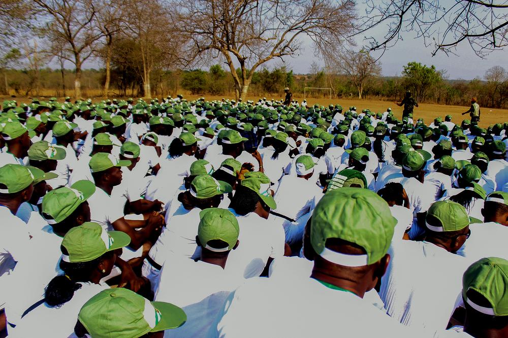 Soldiers address a group of corpers (trainees) while they crouch. 