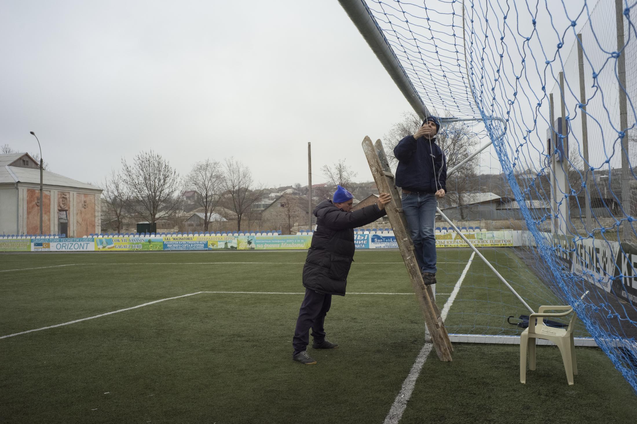 Republic of Moldova / Gagauzia / Cead&icirc;r-Lunga / The equipment manager of FC Saxan is holding the ladder to help repair the goal, one day before the game. He was born in Gagauzia and is very proud of his origin: he believes sport and football can help make the Gagauzian flag more seen and help making the local culture better respected and recognised in the Moldovan state system.