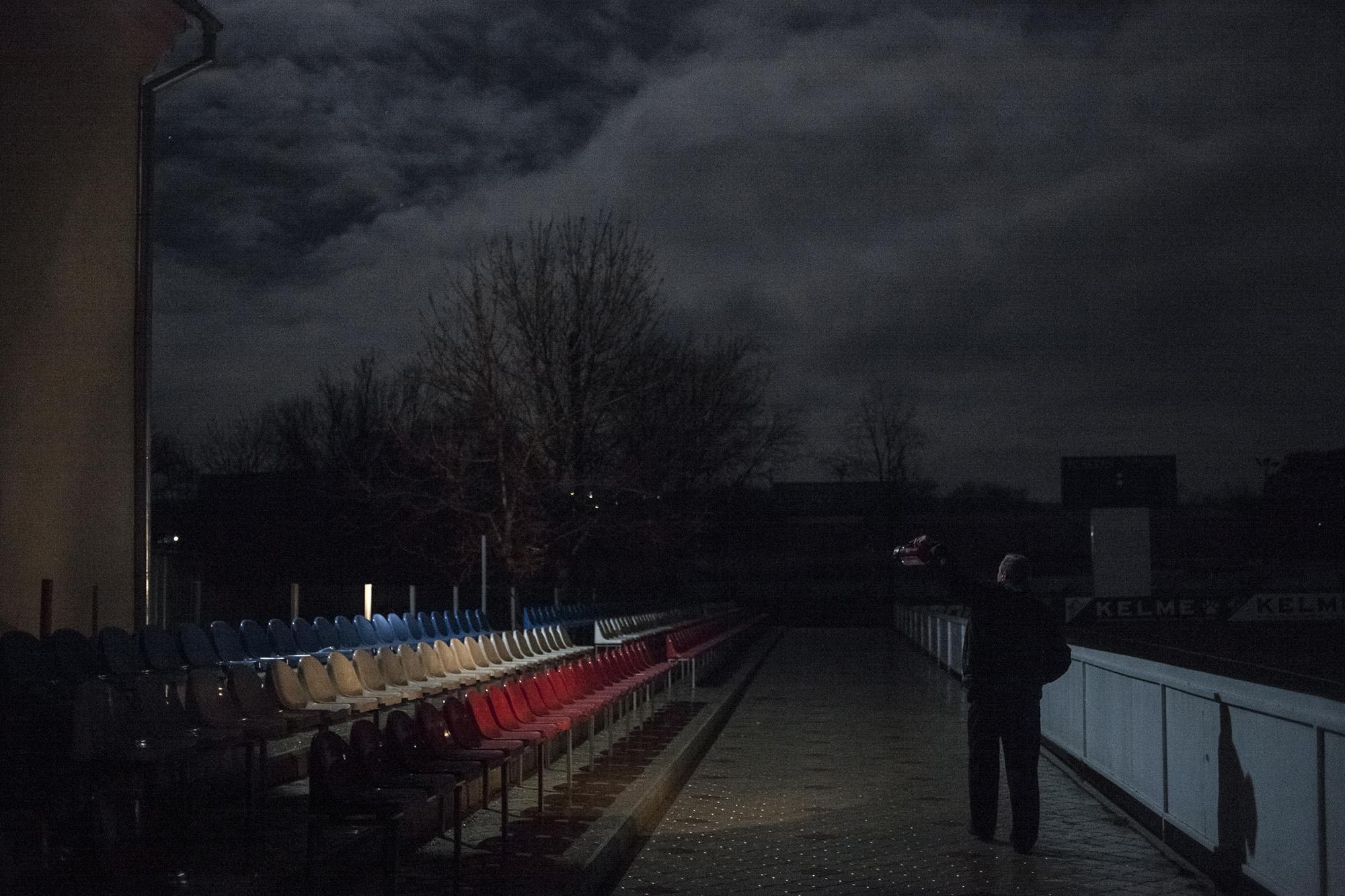 Republic of Moldova / Gagauzia / Cead&icirc;r- Lunga / the keeper of the stadium checks the seats for a round in the evening. The seats have the colors of the Gagauzian flag: blue-white-red.