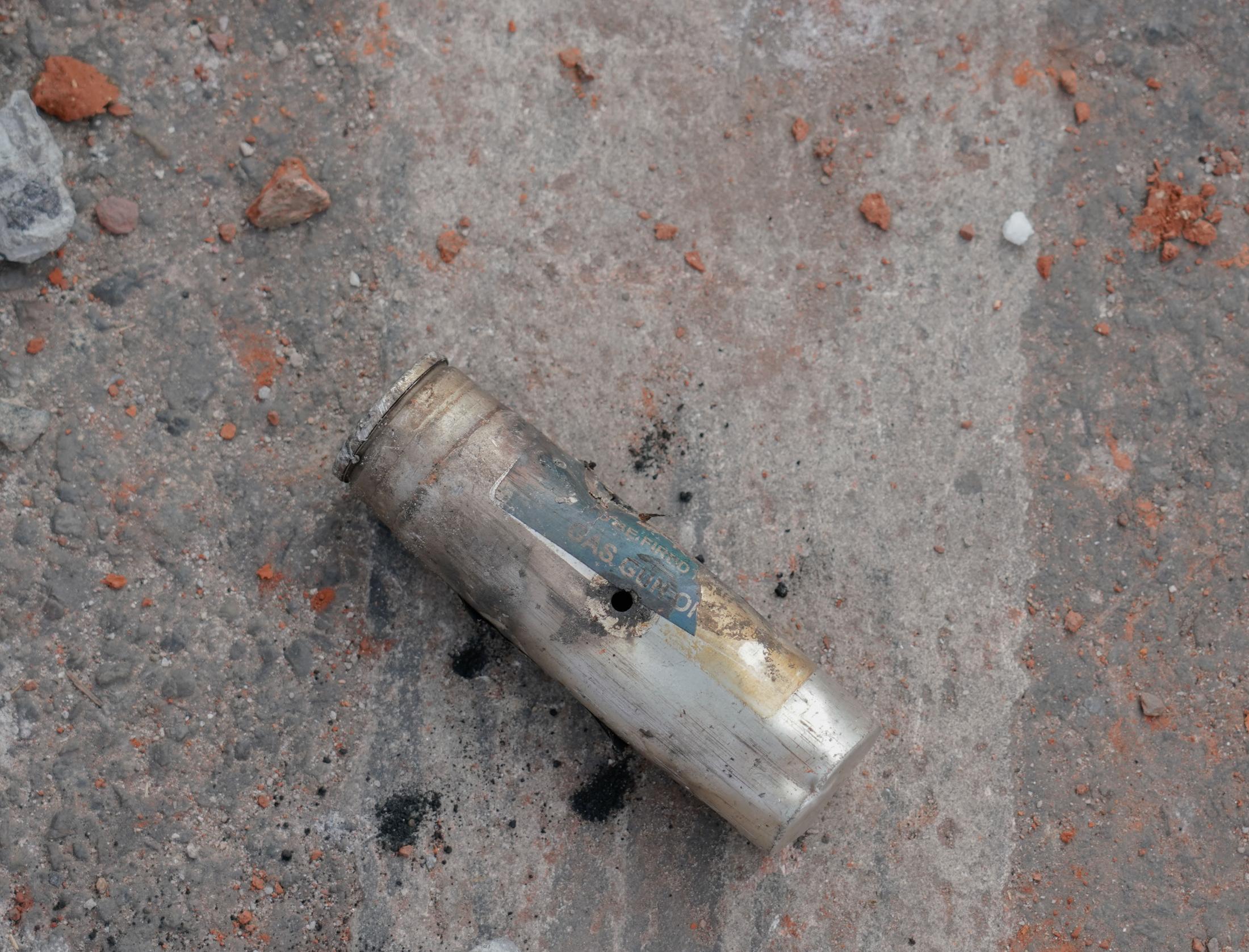 Aazadi - A exhausted tear gas canister sits among the rubble of...