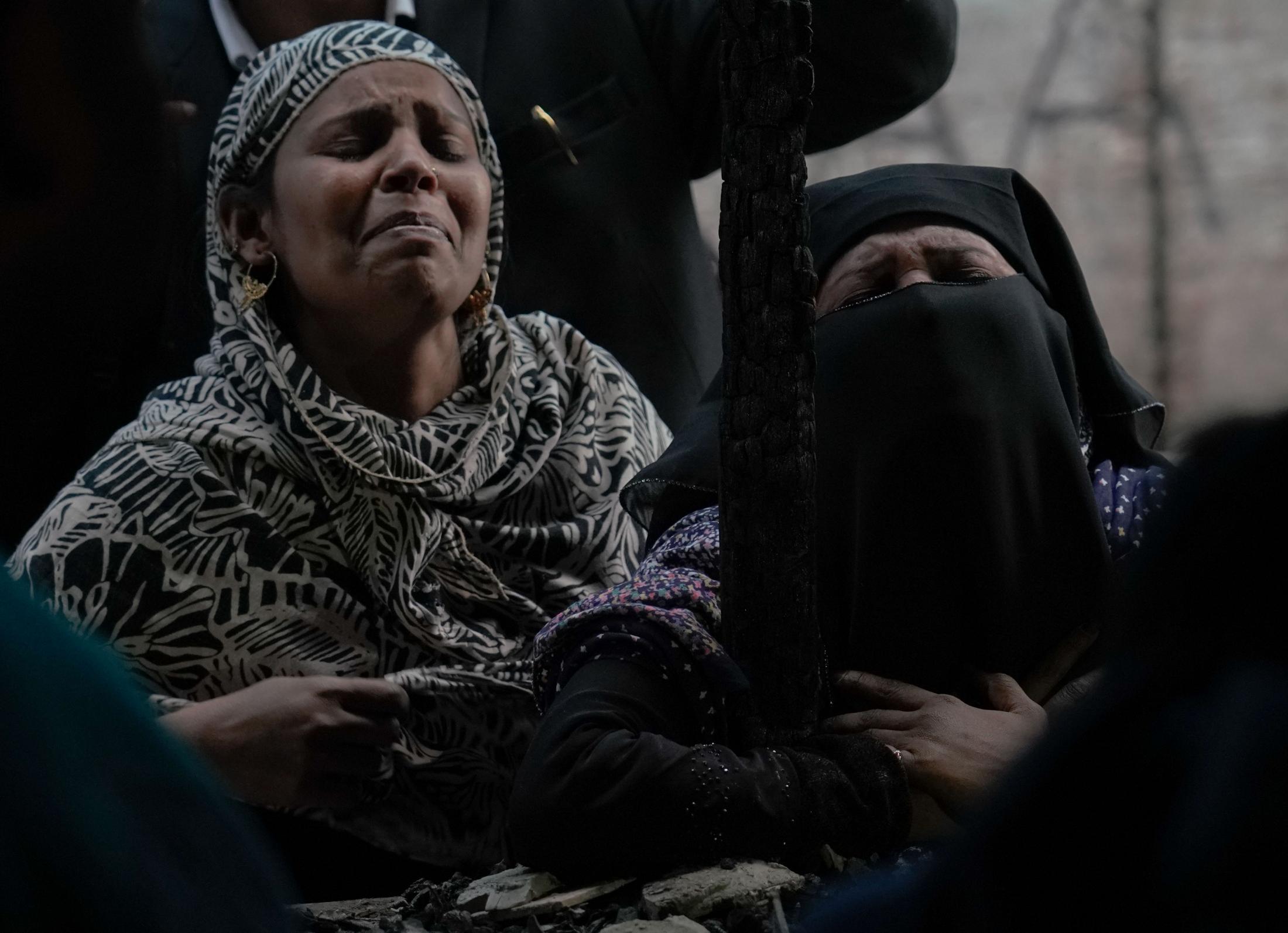 Aazadi - Muslim women cry outside their charred mosque after it...
