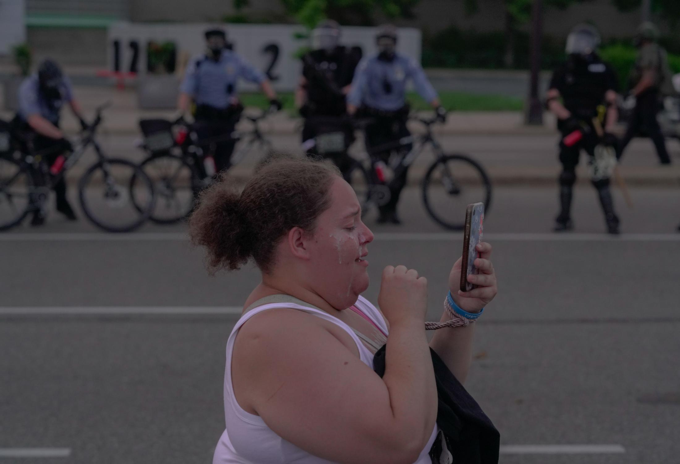 The BLM Summer - A woman who has been pepper sprayed walks by a group of...