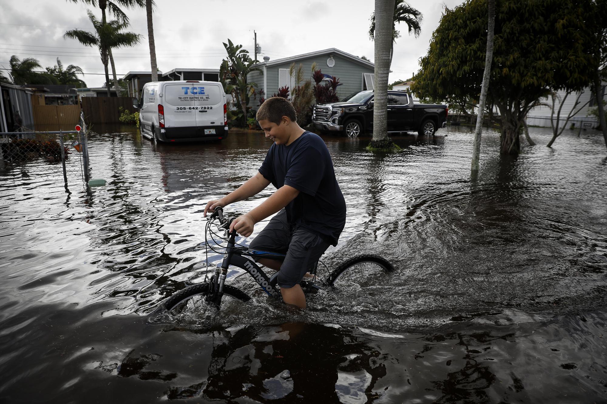 Tropical Storm Eta drenches South Florida - A boy rides a bicycle in floodwaters caused by Storm Eta...