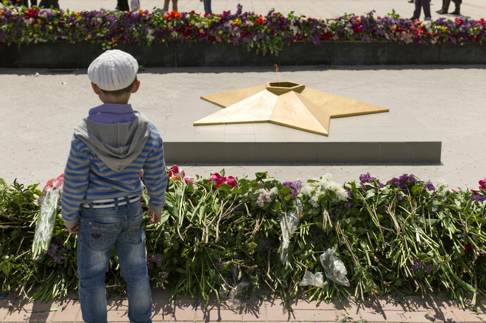 Victory Day in Transnistria - A child stands in front of the eternal flame surrounded...