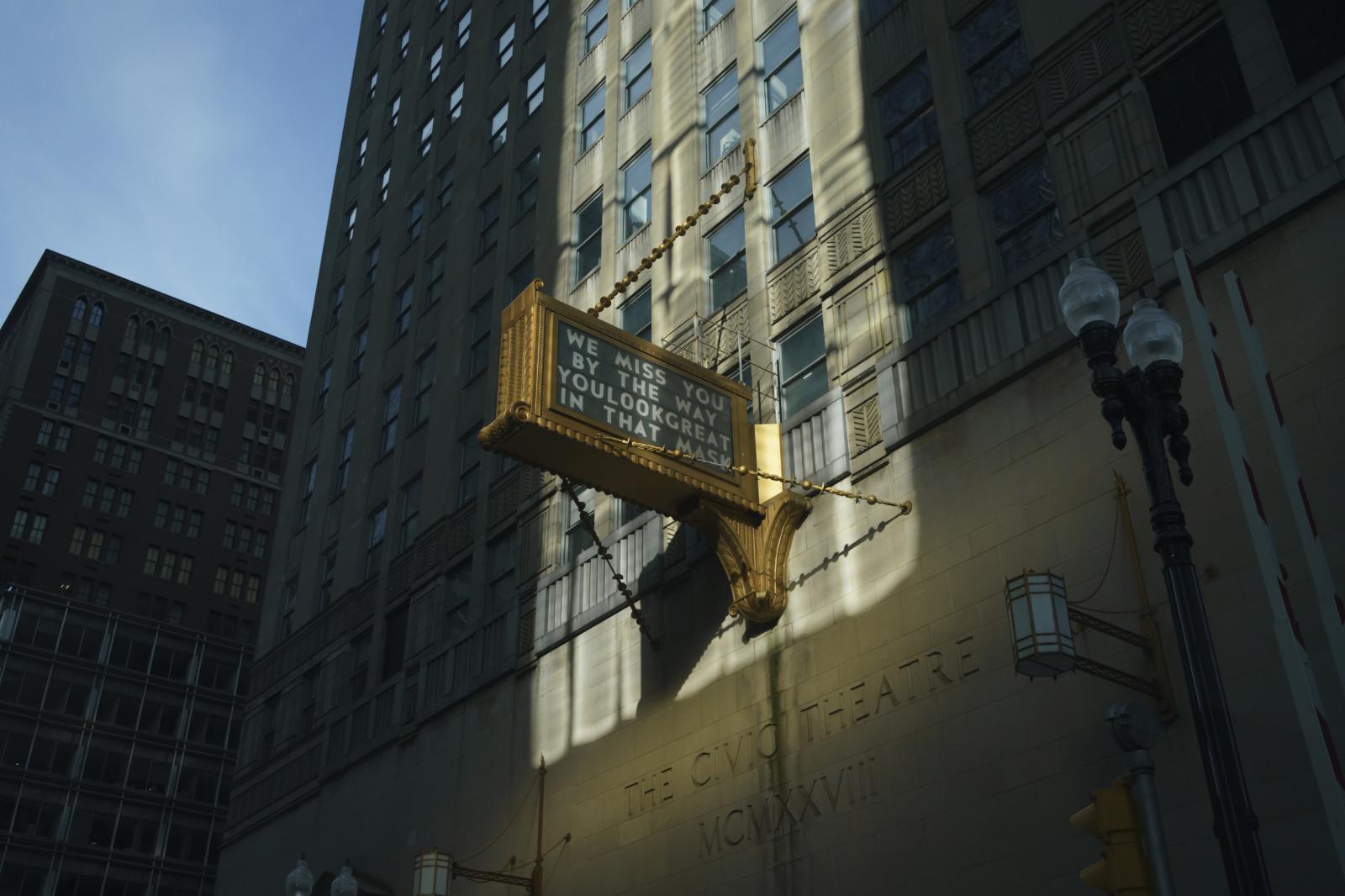 Portfolio - A beam of sunlight through buildings illuminates a sign...