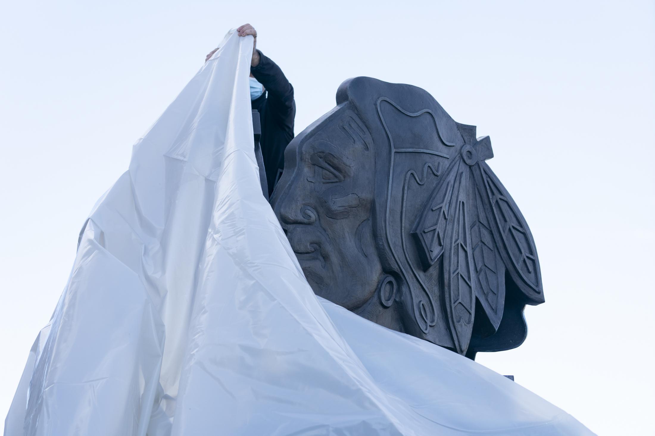 The New Reality - A crew member covers up the Blackhawks logo statue...