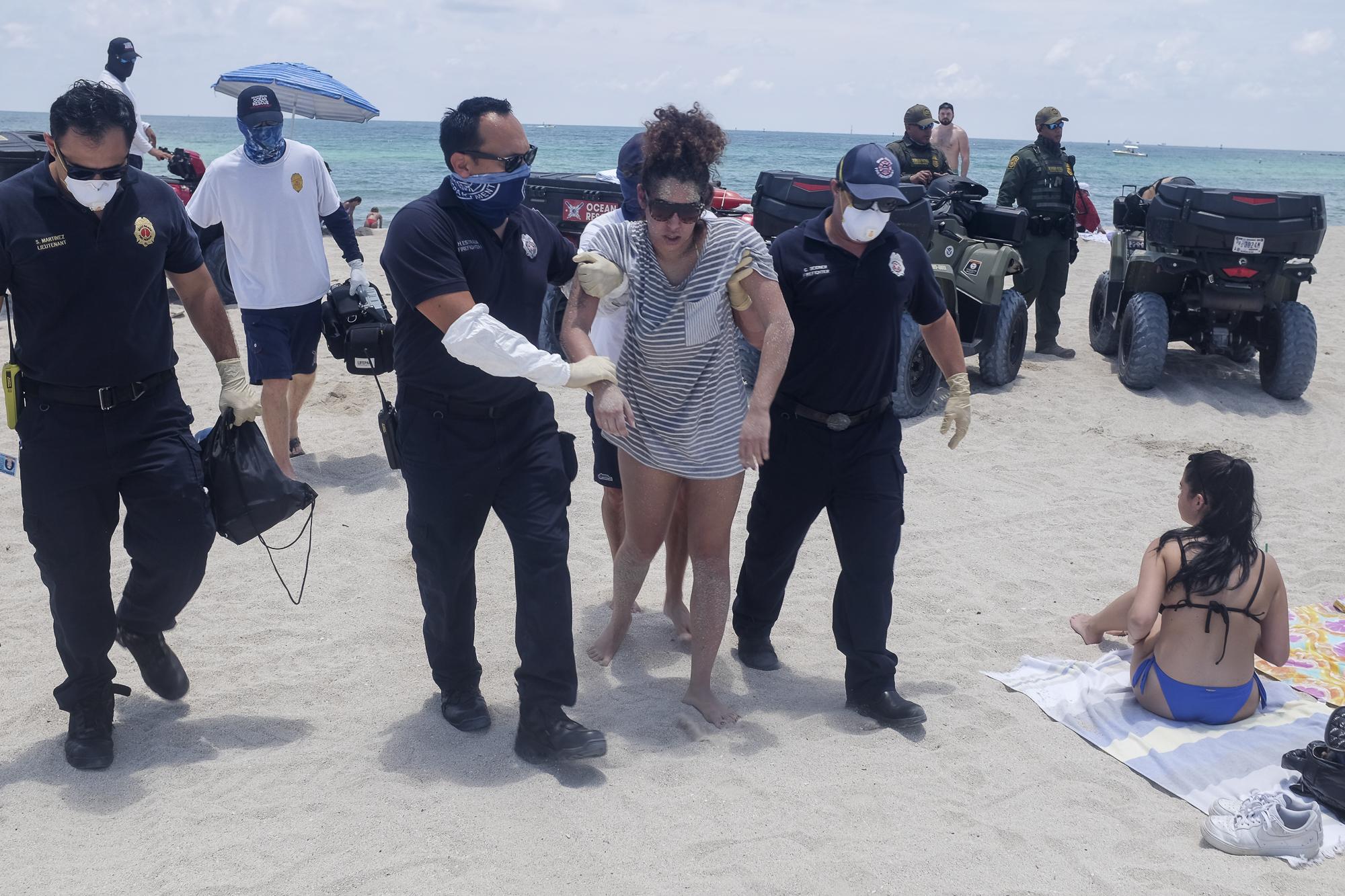 Beaches reopen with restrictions to limit the spread of the coronavirus disease  - First responders assist a woman after fainting as beaches...