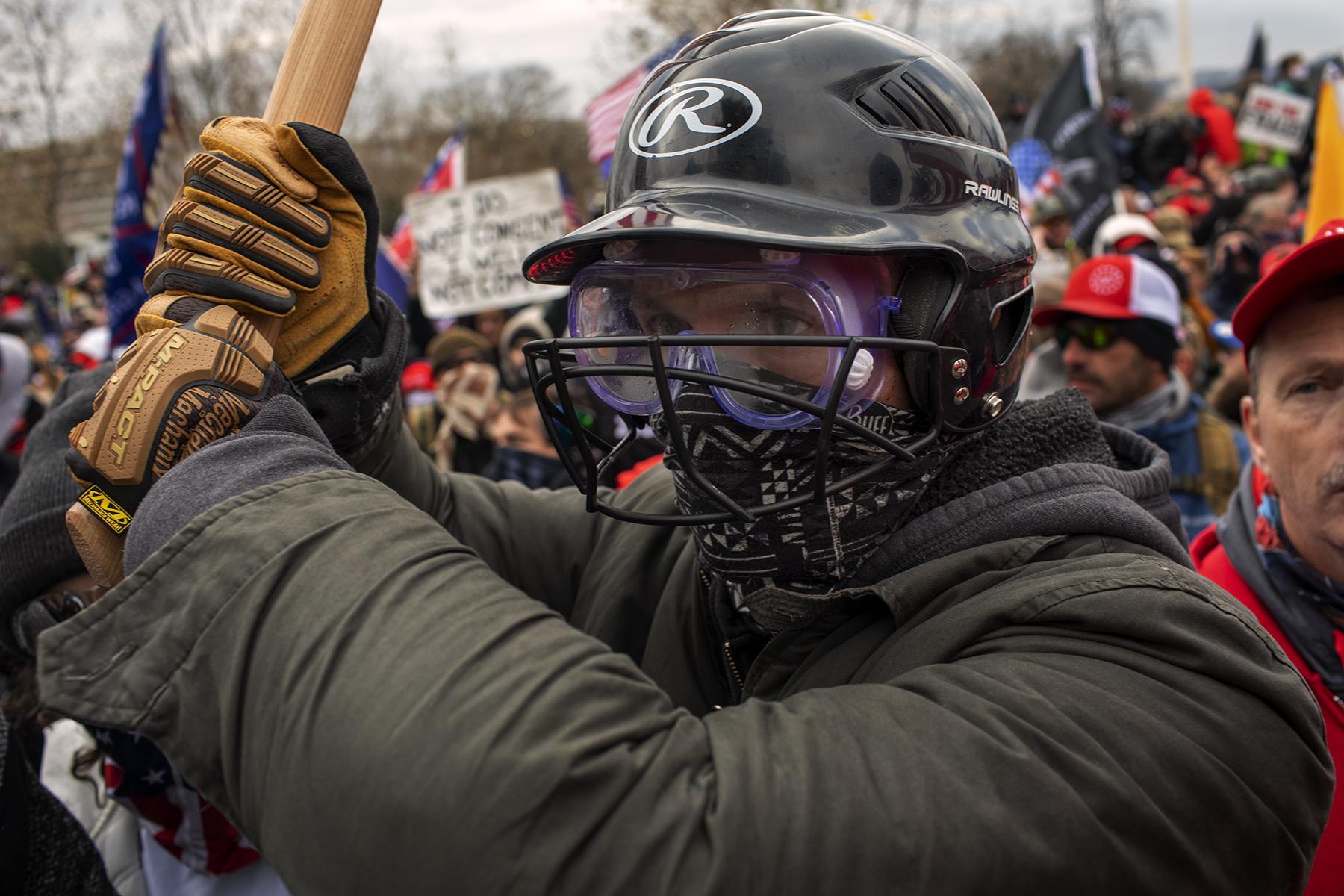 Protests, Pestilence & Politics - A insurrectionist wields an ax handle.