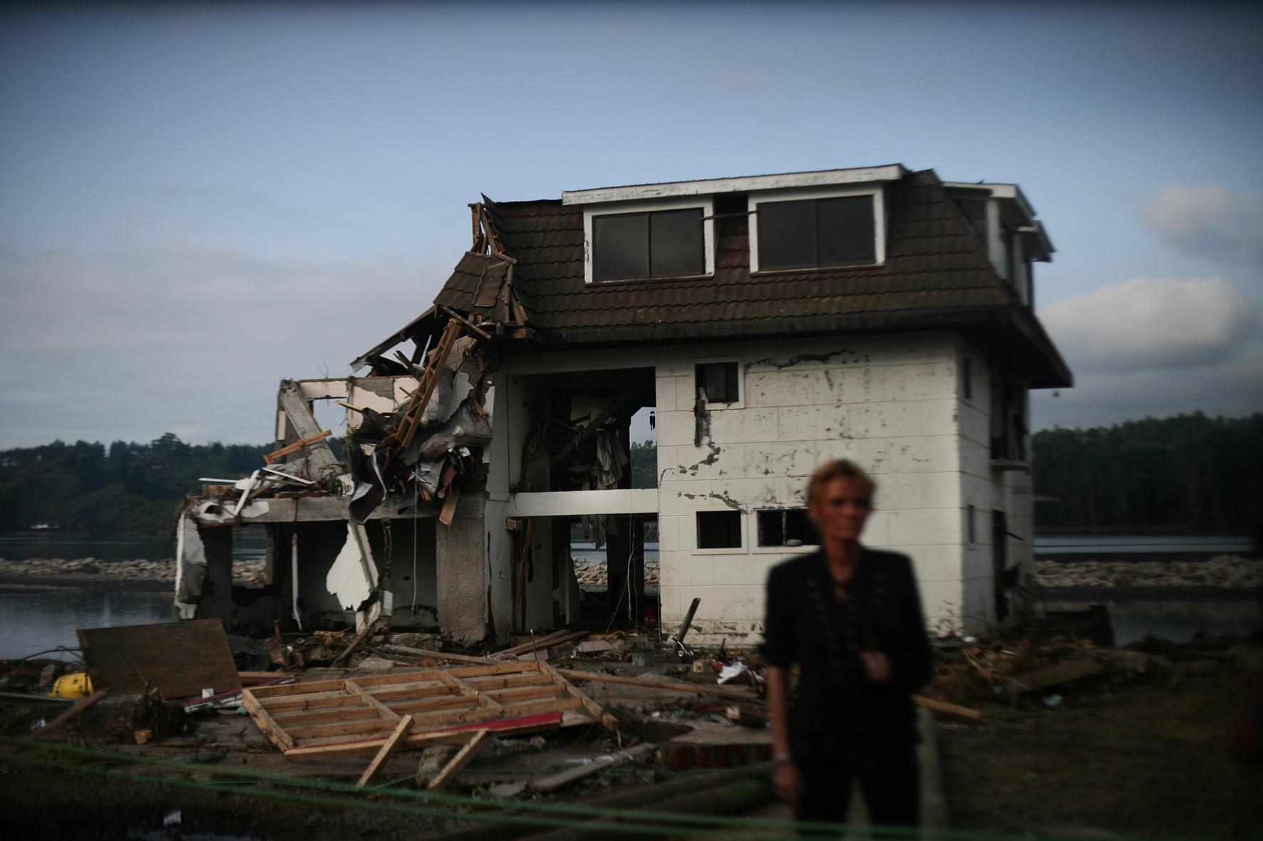 una periodista raliza un enlace enfrente de un hotel destruido por el tsunami en constitucion